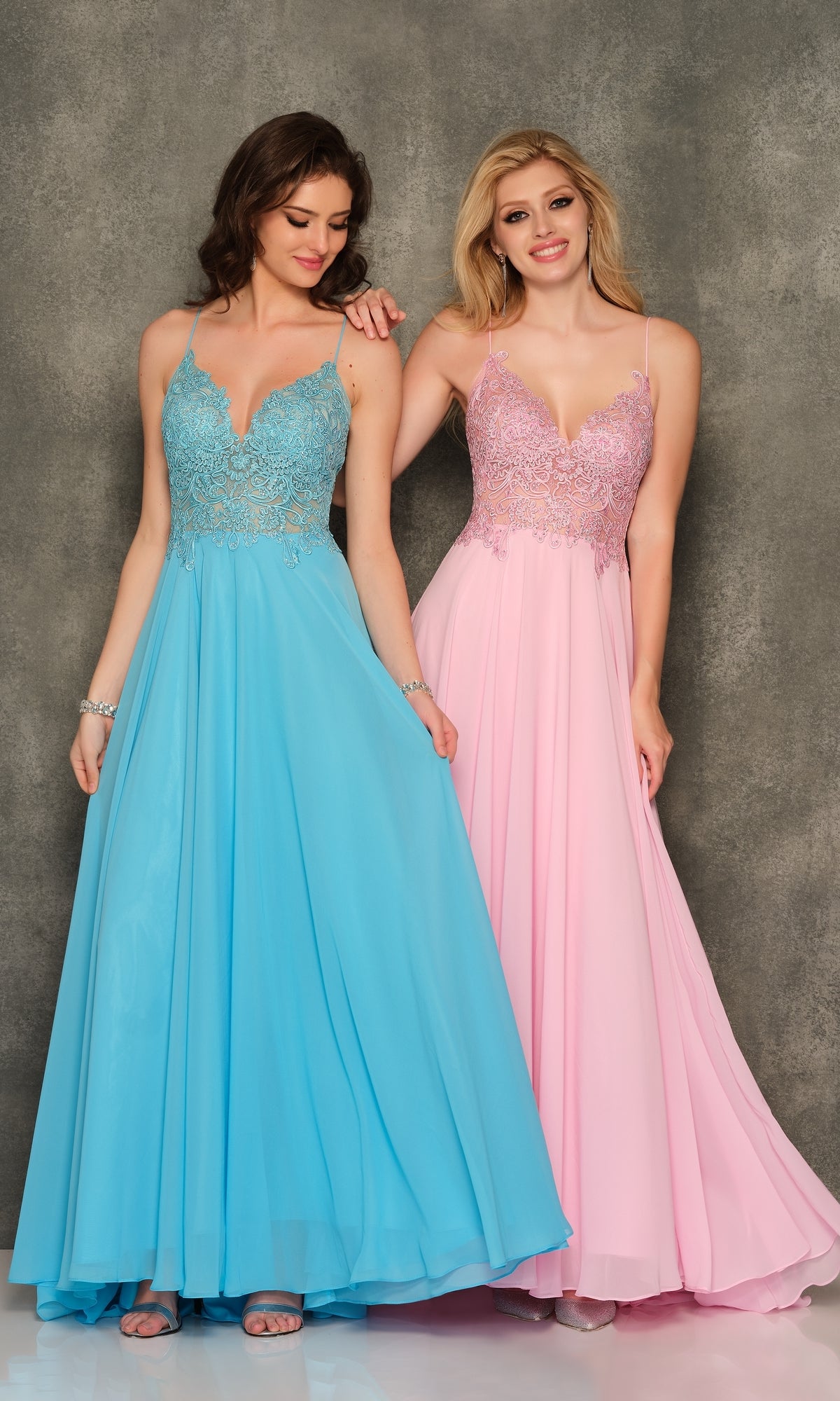 Two women stand side by side in Classic Long A-Line Prom Gown: Dave & Johnny A7248—one in blue, one in pink—each dress featuring an embroidered-lace bodice and spaghetti straps, set against a textured gray backdrop.